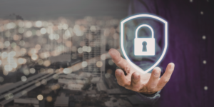Mão segurando escudo com cadeado simbolizando segurança de dados pessoais sob a LGPD com cidade ao fundo